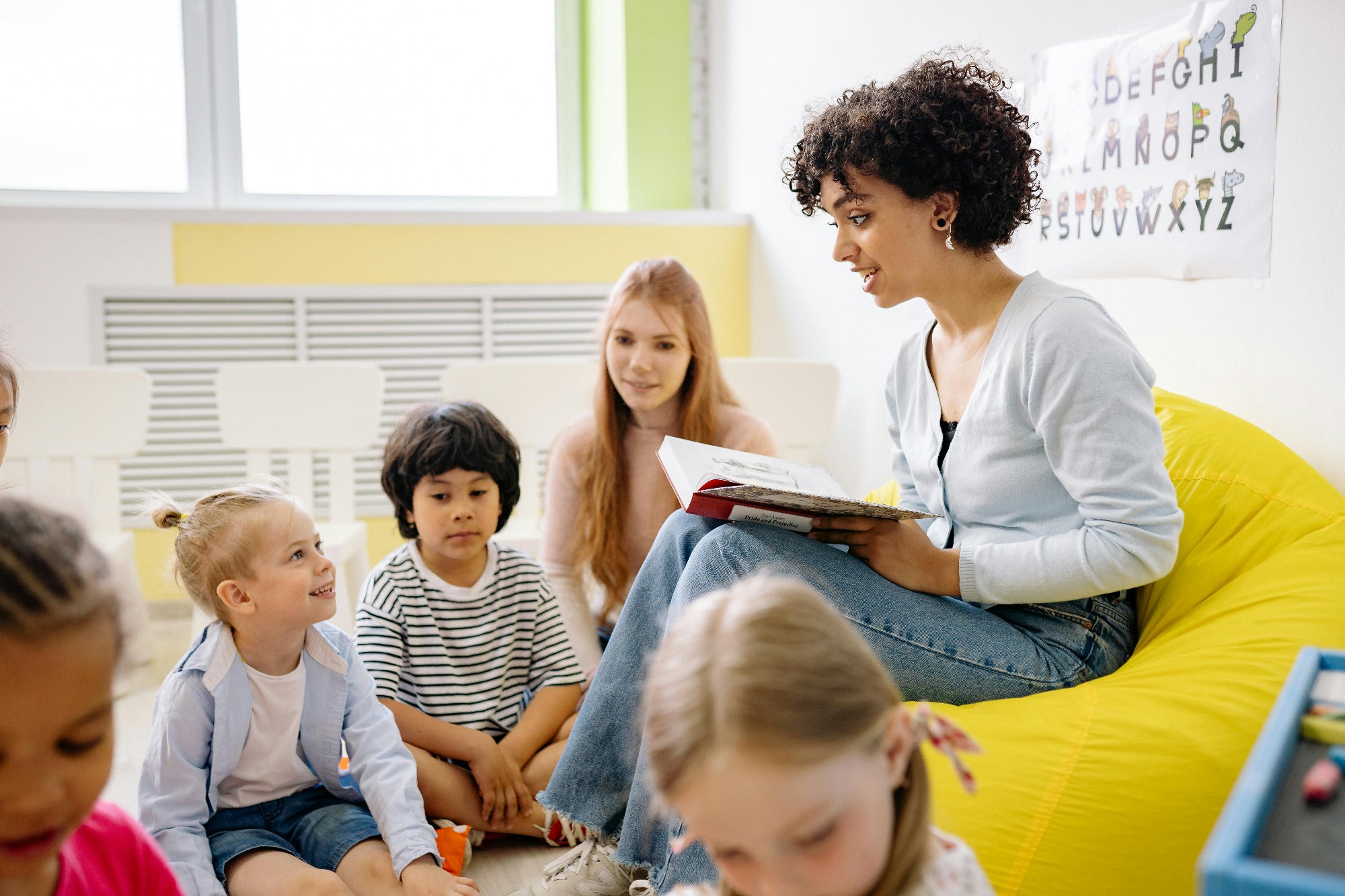A teacher reading a book to her students who are happy to be protected from germs in their classroom by the Airea Space Purifier.