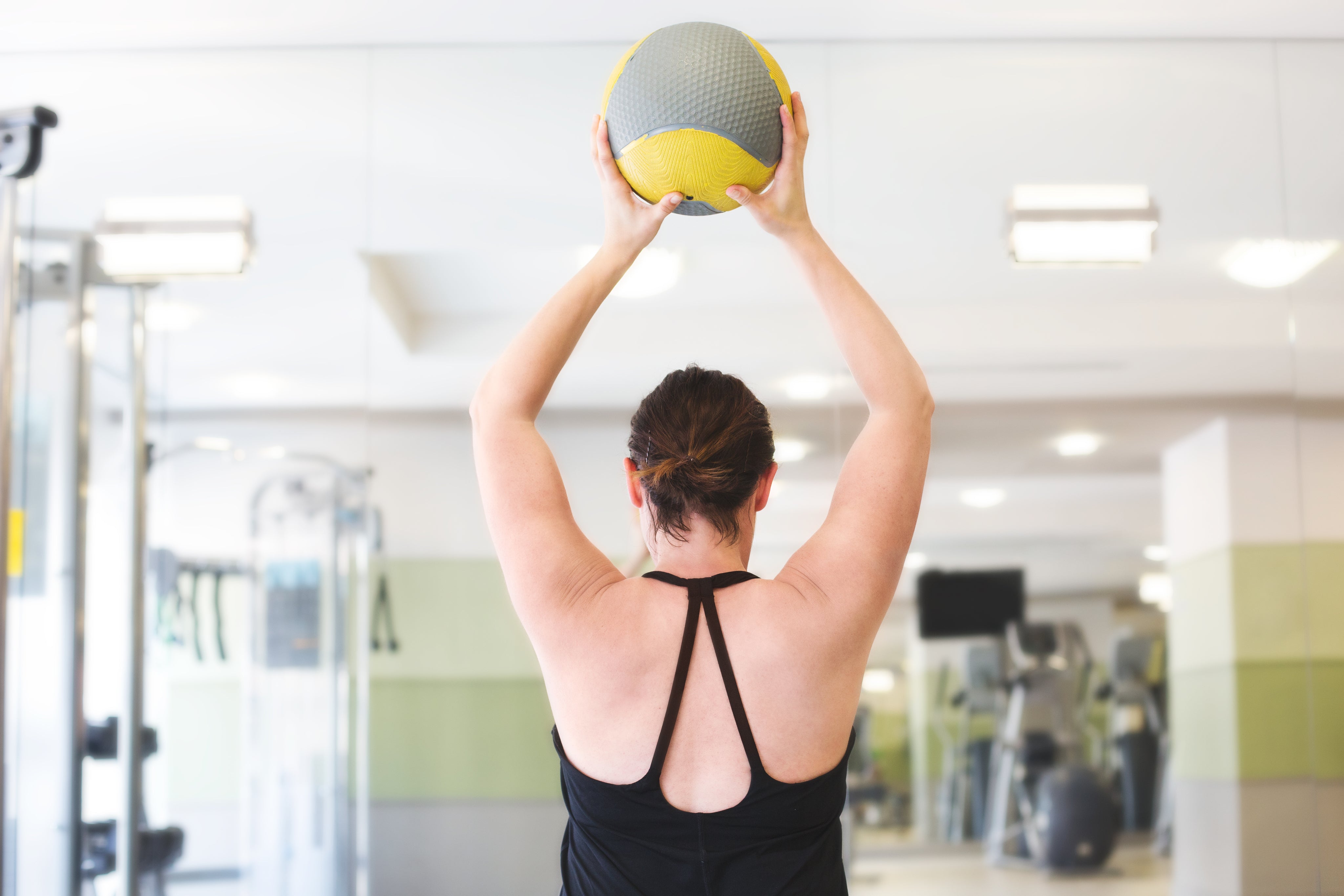 A woman exercising in a clean gym with purified air and sanitized surfaces.