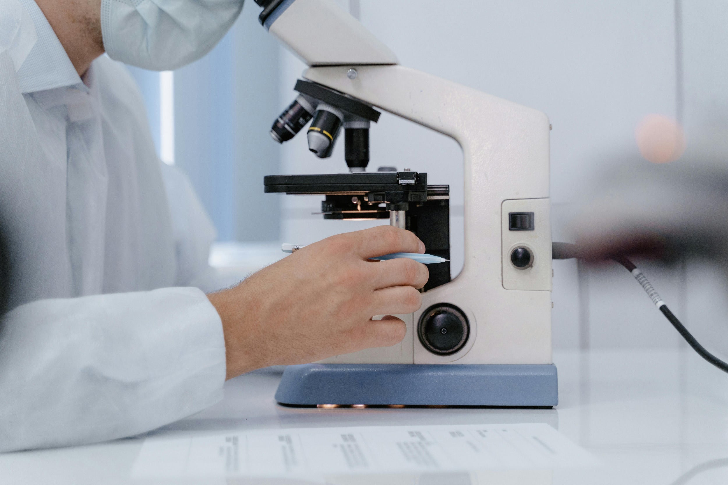 A man peering into microscope used for scientific research.